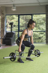Aktive Sportlerin beim Üben mit der Langhantel im Fitnessstudio - MTBF00867