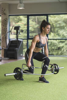 Zielstrebige Sportlerin beim Training mit der Langhantel im Fitnessstudio - MTBF00869