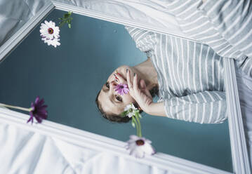 Young woman reflecting in mirror lying on bed - SVCF00011