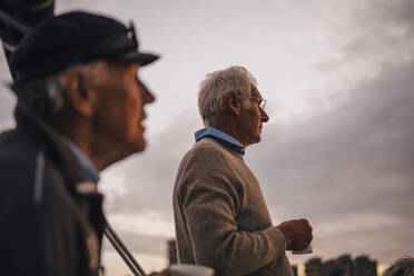 Männliche Freunde mit Kaffeetasse, die bei Sonnenuntergang in den Himmel schauen - MASF22288