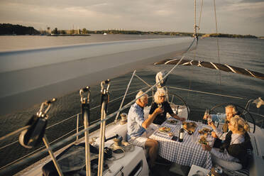 Senior couples toasting wineglasses while spending leisure time in boat - MASF22309