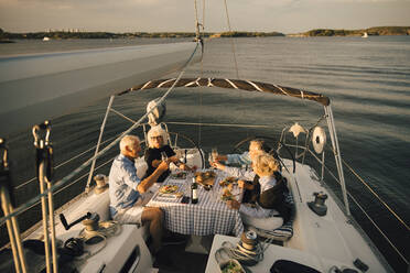 Heterosexual couples toasting wineglasses while spending leisure time in sailboat - MASF22310