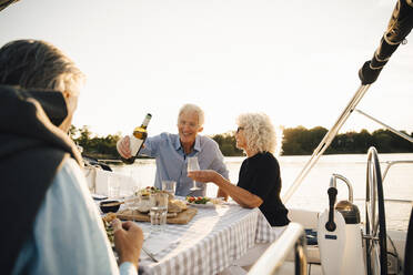 Cheerful senior friends having wine while spending leisure time in sailboat - MASF22314