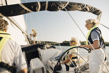 Ältere männliche und weibliche Freunde verbringen ihre Freizeit in einem Segelboot an einem sonnigen Tag - MASF22323