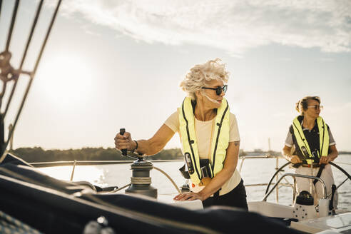 Freundinnen schauen weg, während sie in einem Boot gegen den Himmel segeln - MASF22326