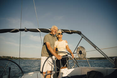 Lächelndes älteres Paar mit Arm um in Segelboot gegen Himmel im Meer - MASF22332