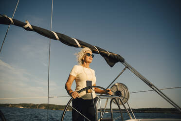 Aktive ältere Frau, die ein Boot gegen den Himmel im Meer segelt, an einem sonnigen Tag - MASF22335