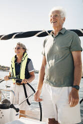 Woman sailing boat standing by senior man on sunny day - MASF22354
