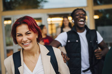 Redhead female student laughing with friends during sunset - MASF22437