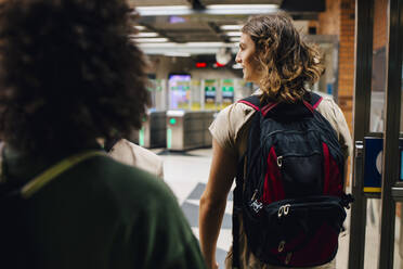 Rückansicht eines männlichen und eines weiblichen Studenten, die an einer U-Bahn-Station gehen - MASF22449