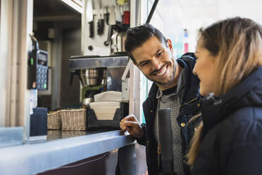 Smiling couple talking with each other at food truck - MASF22489