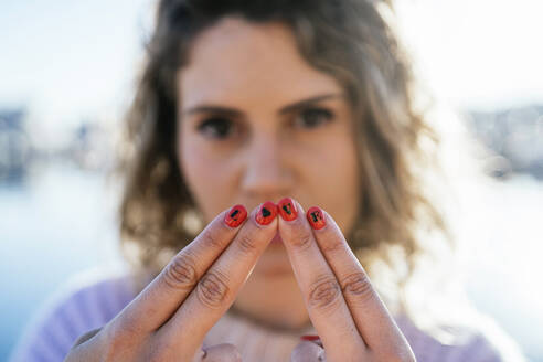 Frau zeigt Alphabete auf Fingernägeln gegen den Himmel - MPPF01558
