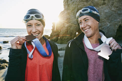 Zwei Schwestern, Triathletinnen im Training in Badekleidung, die ihre großen Medaillen tragen, Gewinnerinnen. - MINF16065