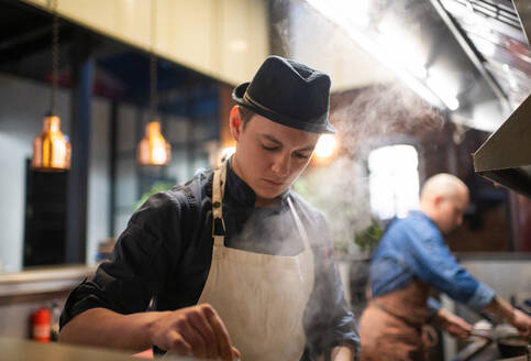 Young chef preparing food in kitchen - CAVF93616