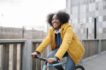 Smiling woman cycling on footpath - JCZF00509