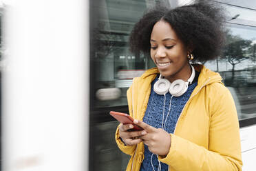 Young woman text messaging on smart phone while standing by tram - JCZF00516