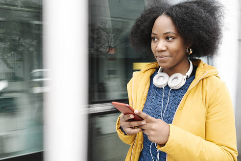 Lächelnde Frau mit Mobiltelefon in der Straßenbahn - JCZF00517