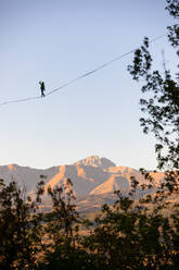 Slackliner auf dem Gran Sasso mit Bäumen im Vordergrund - CAVF93686