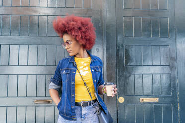 Frau mit rotem Afro-Haar trinkt ihren Kaffee auf der Straße - CAVF93702