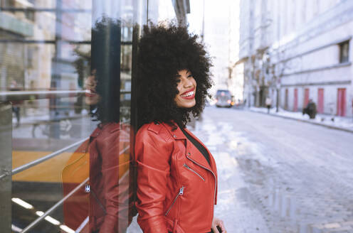 Fill body side view of confident African American female with Afro hairstyle standing on sidewalk and looking away - ADSF21161