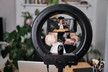 Woman applying make-up while filming make-up tutorial at home - ASGF00036