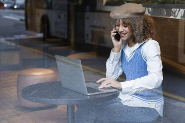 Teenager-Mädchen mit Laptop, das in einem Café mit einem Mobiltelefon spricht - PNAF00920