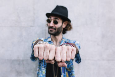 Caucasian man showing knuckles while standing in front of wall - XLGF01287