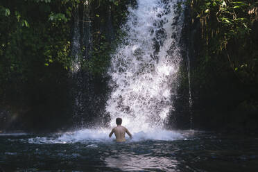 Indonesien, Bali, Mann beim Baden im Wasserfall - KNTF06176