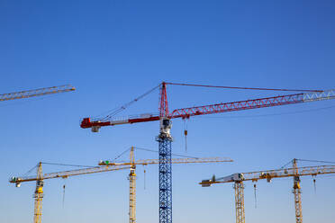 Germany, Bavaria, Munich, Construction cranes against blue sky - MAMF01668