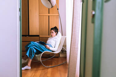 Young woman sitting in a chair and reading - CUF57898