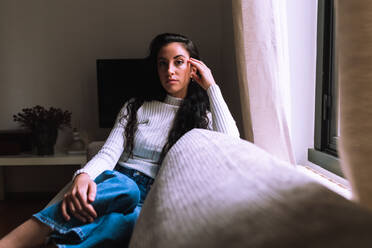 Serious young woman sitting on sofa - CUF57905