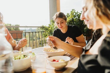 Freunde essen eine Mahlzeit auf dem Balkon - CUF57922