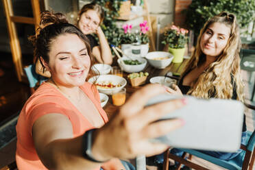 Friends taking selfie at meal on balcony - CUF57924