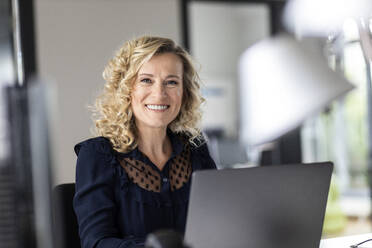 Beautiful smiling female entrepreneur with laptop in office - PESF02661