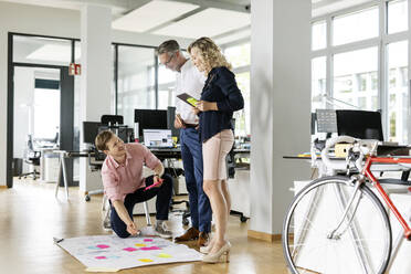 Male and female entrepreneurs assisting business project to colleague in open plan office - PESF02666