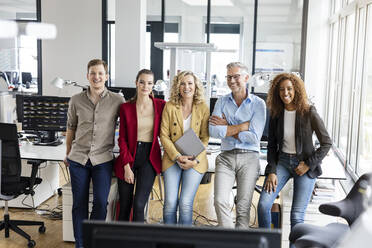 Smiling male and female entrepreneurs leaning on desk in office - PESF02712