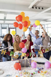 Female entrepreneur taking selfie while celebrating birthday at desk in office - PESF02716