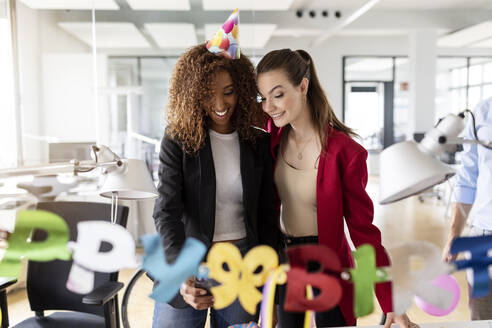 Female business professionals celebrating birthday in office - PESF02717