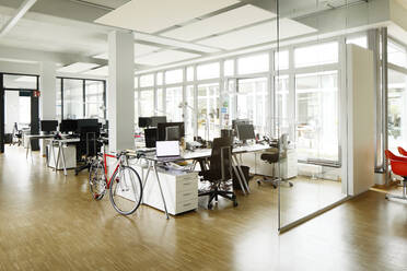 Bicycle at desk in open plan office - PESF02745