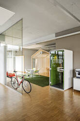 Bicycle leaning on glass wall in open plan office - PESF02750