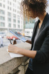 Junge Geschäftsfrau schreibt mit digitalem Tablet in ihr Tagebuch - BOYF01951