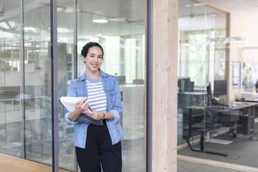 Smiling businesswoman with document at office - FKF04040