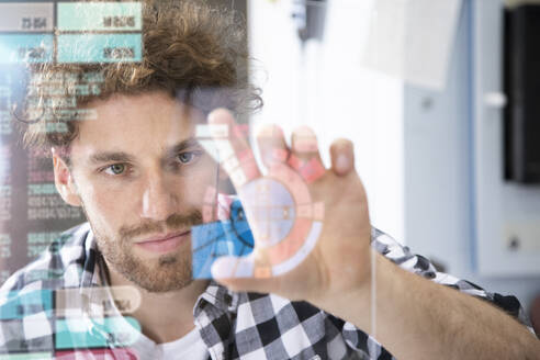 Young male entrepreneur touching projection screen in factory - FKF04092