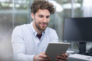 Young male entrepreneur using digital tablet at office - FKF04103