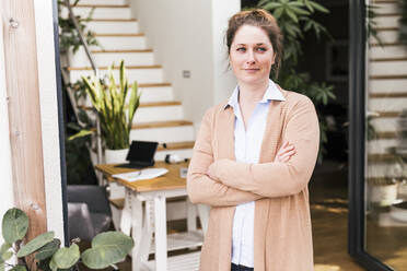 Smiling woman standing with arms crossed at home - UUF22936