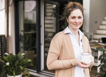 Mittlere erwachsene Frau steht und hält eine Kaffeetasse - UUF22939