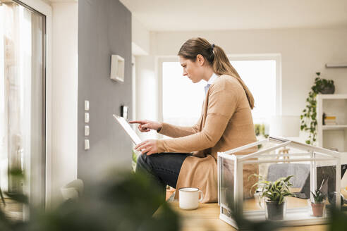 Berufstätige Frau mit Laptop auf dem Schreibtisch zu Hause - UUF22942