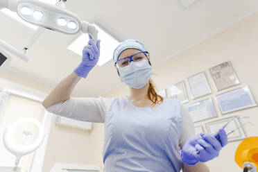 Portrait of female dentist wearing protective face mask working at office - EYAF01552