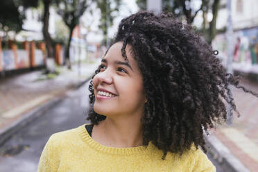 Happy thoughtful woman with curly black hair looking away - DSIF00367