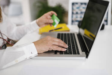 Frau hält Kreditkarte für Online-Zahlung über Laptop zu Hause - EGAF02051